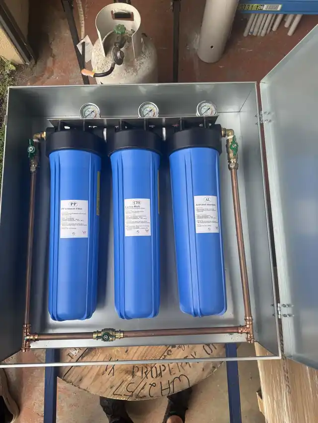 Inside the Dolphin enclosure: three blue filter housings labelled PP, CTO and AL, joined by copper pipework