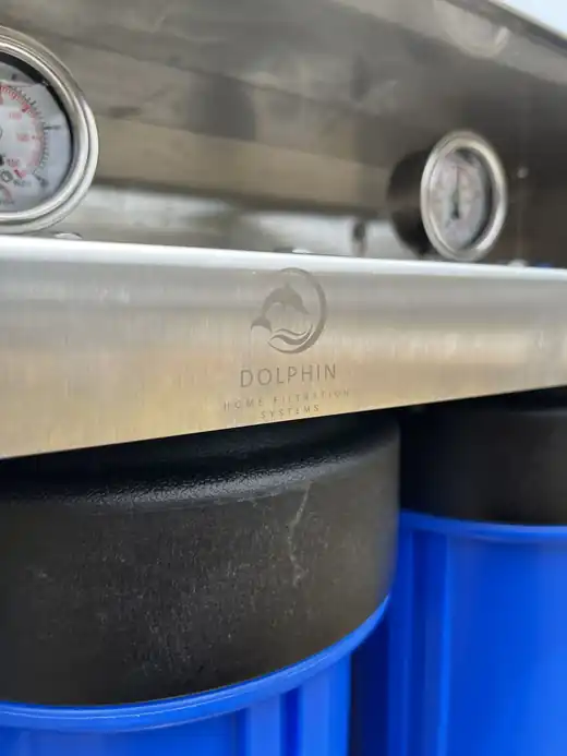Close-up of the Dolphin mark laser-engraved into the brushed stainless enclosure lid, with a pressure gauge alongside