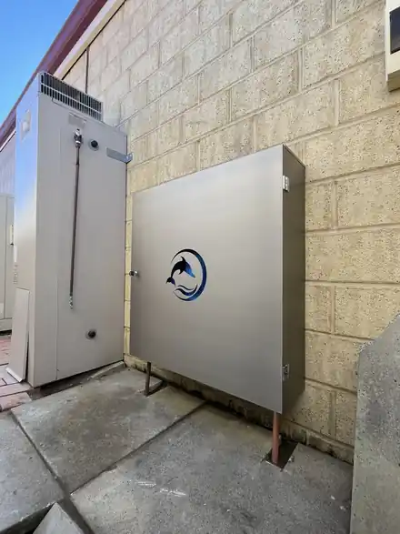 Dolphin enclosure installed alongside a hot water system against a limestone wall