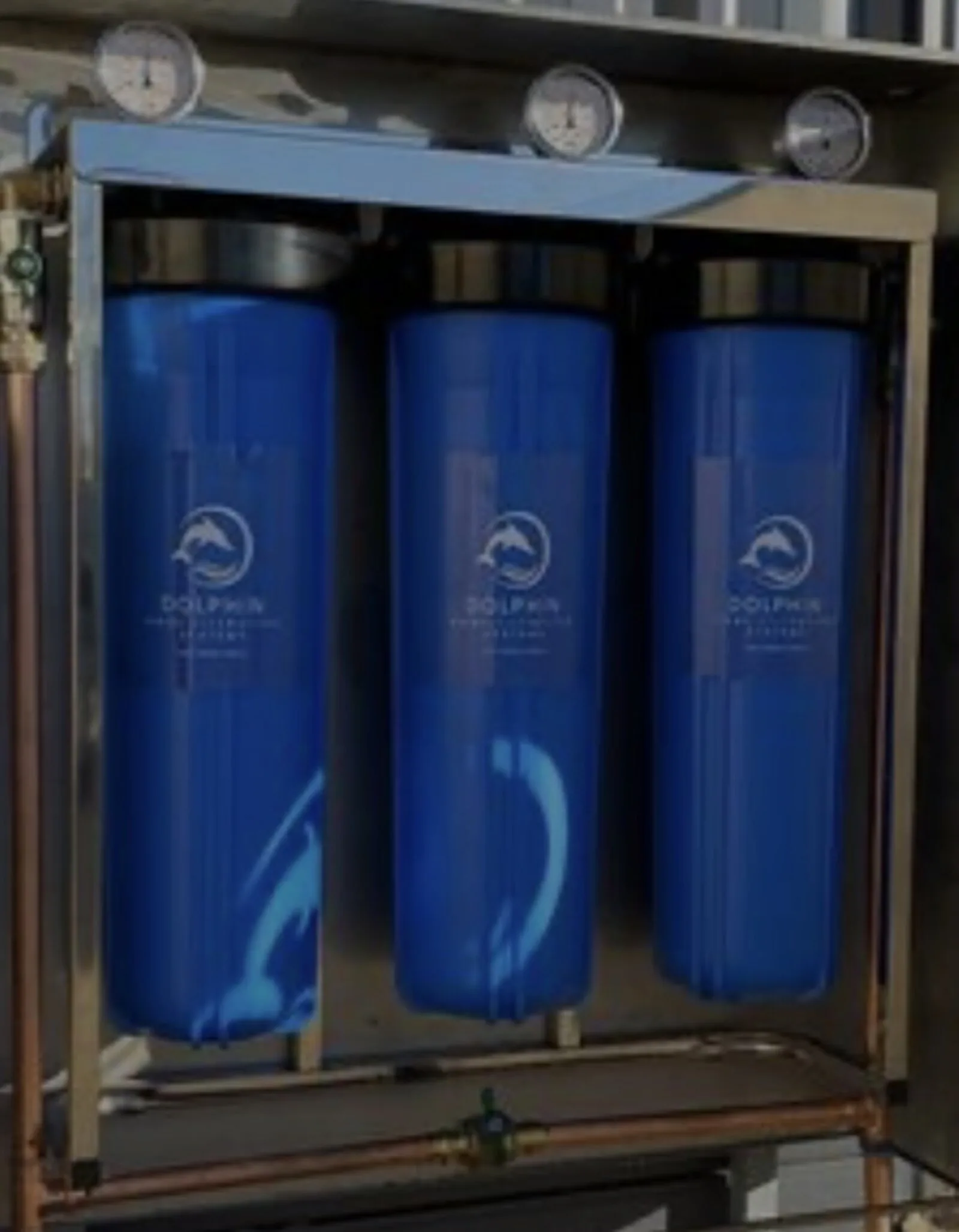 Three Dolphin cartridge housings with pressure gauges and copper pipework inside the stainless enclosure