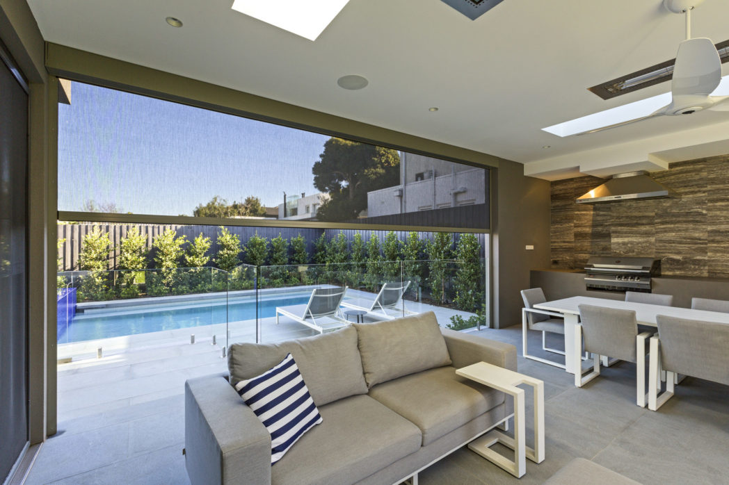 View from inside an alfresco through a Zipscreen mesh blind to a pool and garden